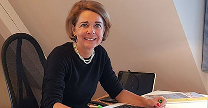 Frau Droemer sietzt von Lernmaterial umgeben am Schreibtisch