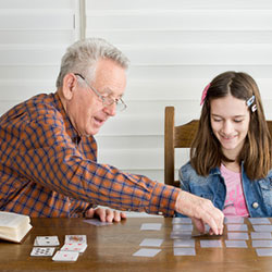 ein älterer Herr spielt mit einem jungen Mädchen Memory